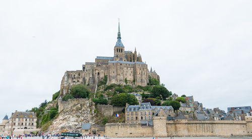 Tourists on top of historic building against sky