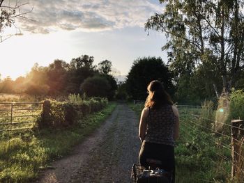 Rear view of woman on field against trees