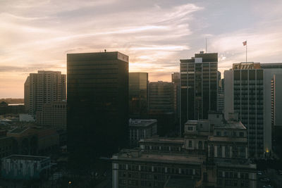 Modern buildings in city against sky during sunset