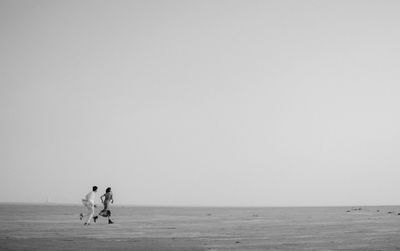 People at beach against clear sky