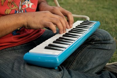 Midsection of man playing synthesizer on field