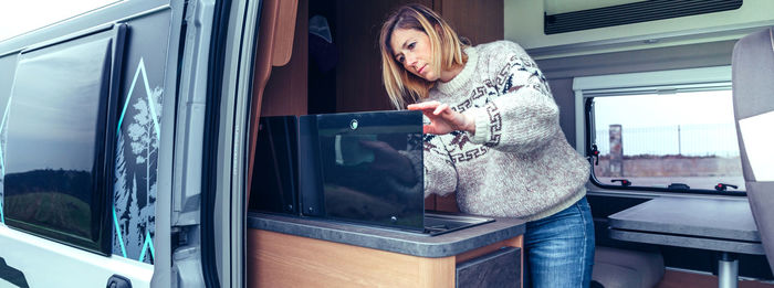 Side view of young woman looking through window