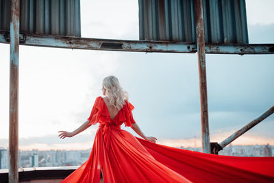 Woman with red umbrella standing by window