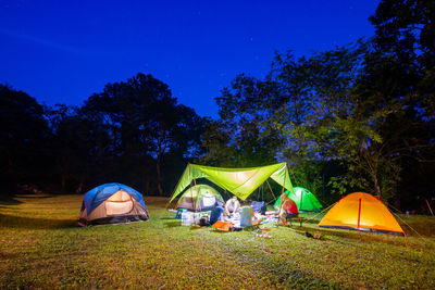 Tent on field by trees against sky at night