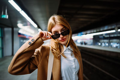 Outdoor portrait of a young beautiful confident woman posing the train station on the background