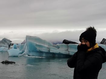 Woman standing in frozen sea against sky during winter