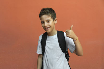 Portrait of smiling boy standing against orange wall