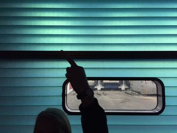 Silhouette man gesturing against window amidst turquoise wall