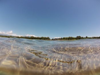 Surface level of beach against clear blue sky