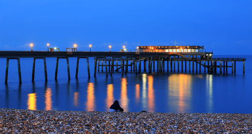 Pier over river against sky at night