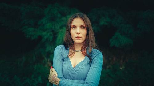 Portrait of young woman standing against trees