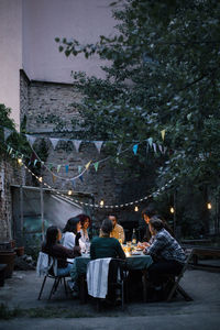 Group of friends enjoying during dinner party in decorated back yard