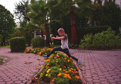 Boy jumping over flowerbed at park