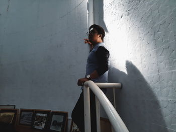 Man looking away while standing against wall