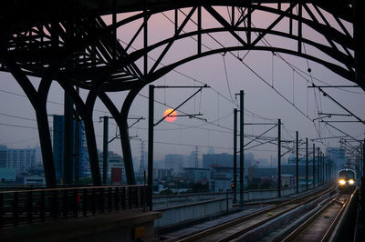 Railroad tracks in city against sky at dusk