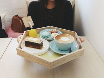 Close-up of woman holding coffee cup on table