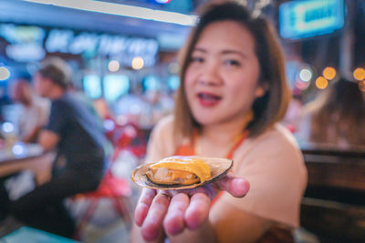 Portrait of woman holding fresh mussel at restaurant