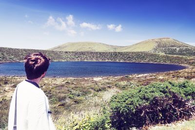 Rear view of man looking at mountain against sky