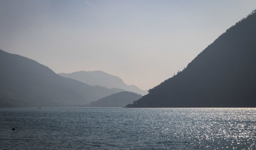 Scenic view of sea and mountains against clear sky