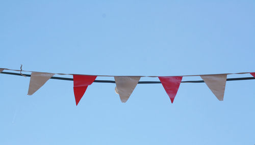 Low angle view of flags against clear sky