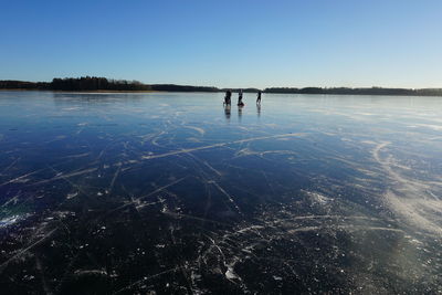 People ice-skating on rink against sky