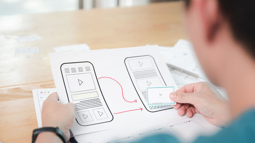 Midsection of man using mobile phone on table