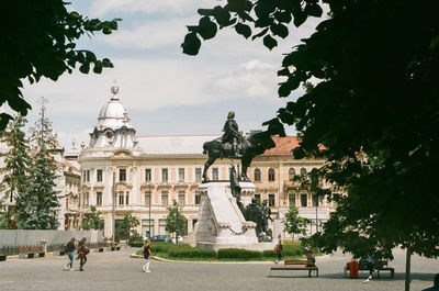 Statue in city against sky