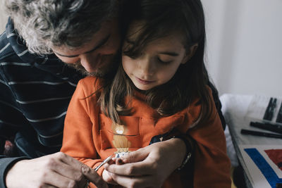 Father cutting nails of daughter with scissor at home