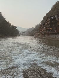 Scenic view of river by buildings against sky