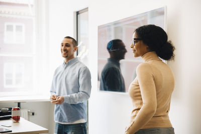 Smiling computer programmers standing by television set during presentation in office