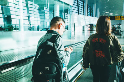 Rear view of man and woman standing on glass window