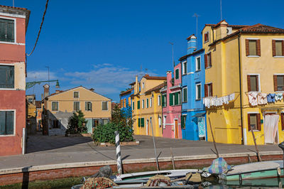 Colorful buildings and boats in front of a canal at burano, a little town full of canals in italy.