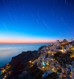 Town by sea against star trails