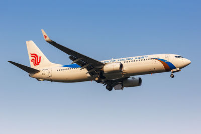 Low angle view of airplane flying against clear blue sky