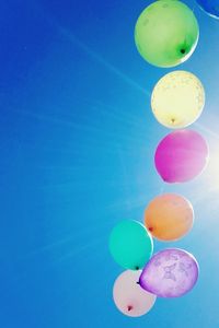 Low angle view of colorful balloons against sunny sky