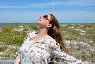 Beautiful young woman wearing sunglasses against sky