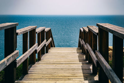 Wooden pier on sea against clear sky