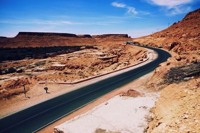 Empty road amidst rocky mountains against sky