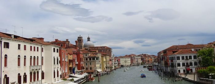 Buildings by canal against sky in city