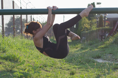 Side view of woman exercising on metallic railing