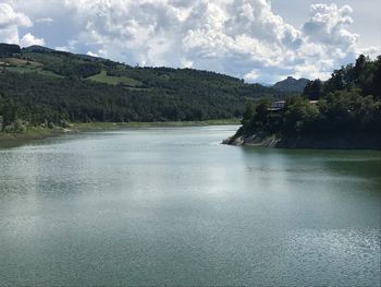 Scenic view of river by mountains against sky