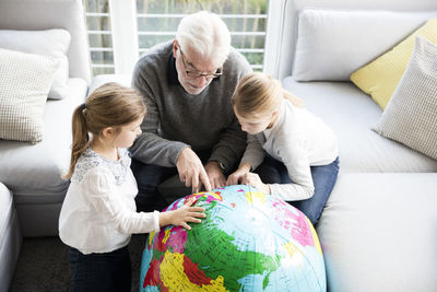 Two girls and grandfather with globe in living room
