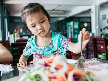 Innocent girl having food at table in restaurant