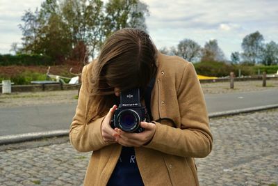 Midsection of woman photographing on street