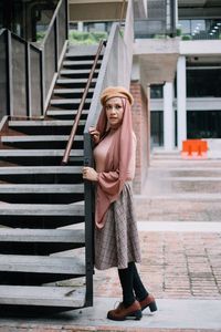 Woman looking away while standing by staircase