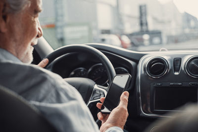 Midsection of senior man using phone while sitting in car