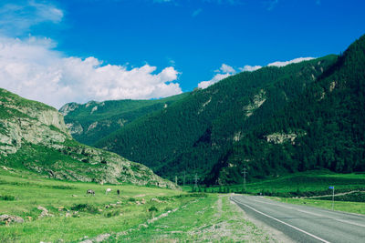 Road passing through landscape against cloudy sky