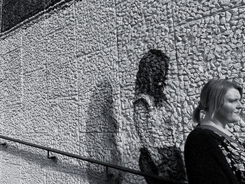 Woman looking away while standing by wall