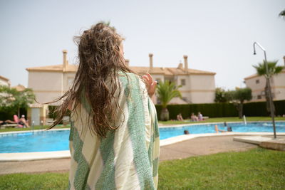 Rear view of girl standing by swimming pool