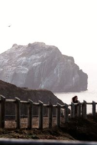 View of rocky mountain by sea against sky
